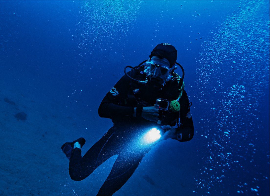 Plongeur en scaphandre avec lampe et appareil photo